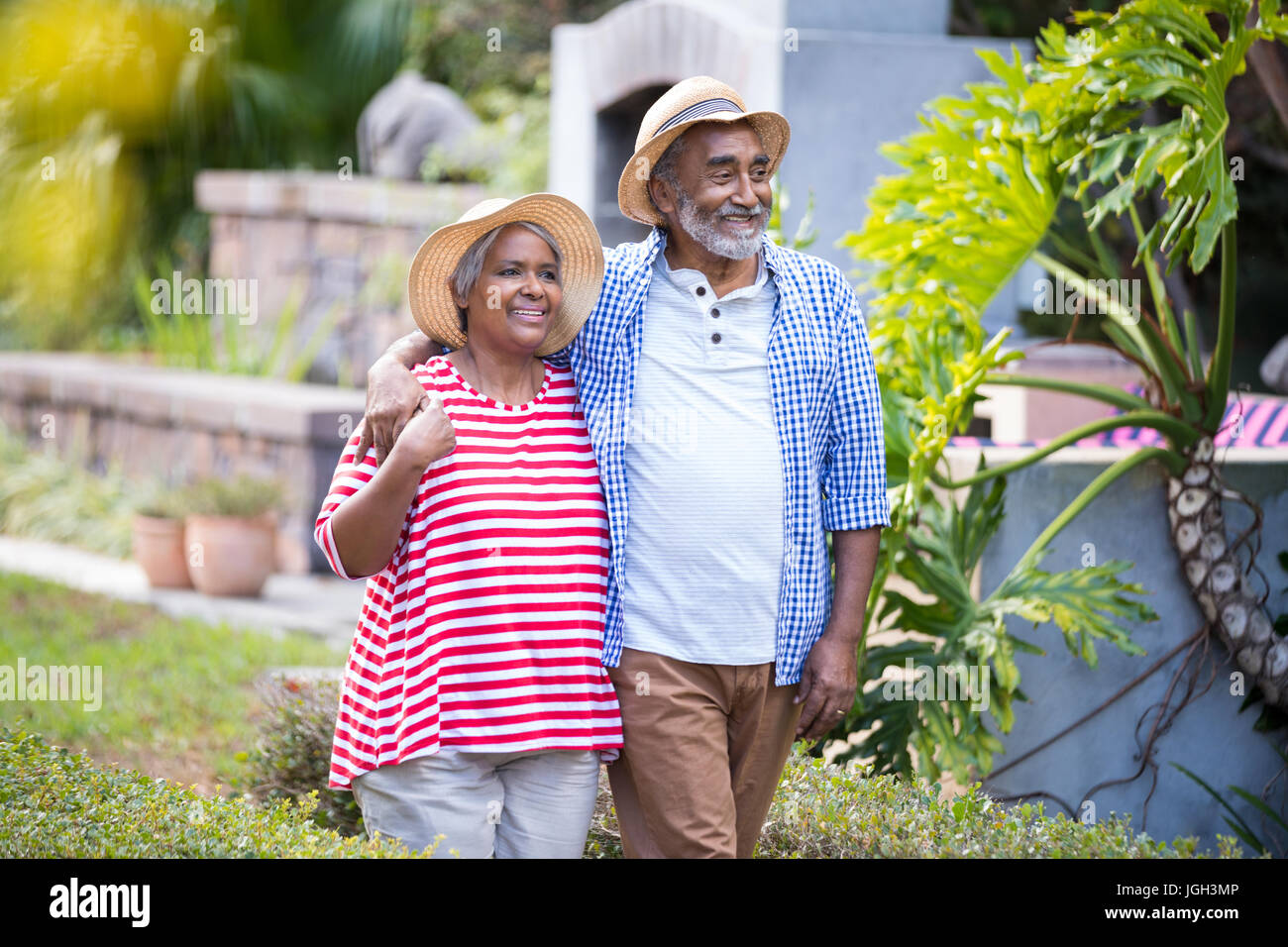 Smiling senior couple with arm around walking in yard Stock Photo