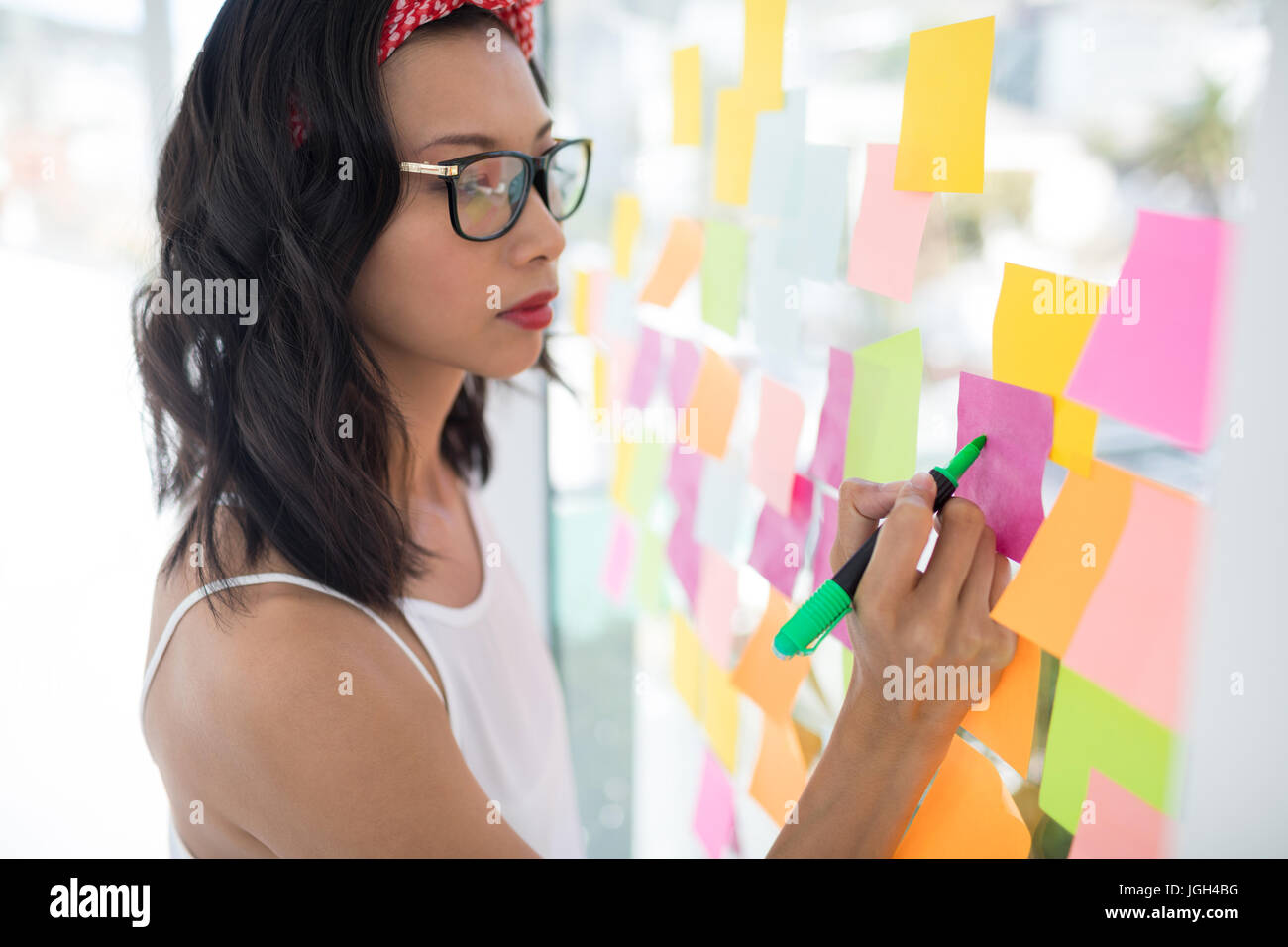 Female executive writing on sticky notes in office Stock Photo - Alamy