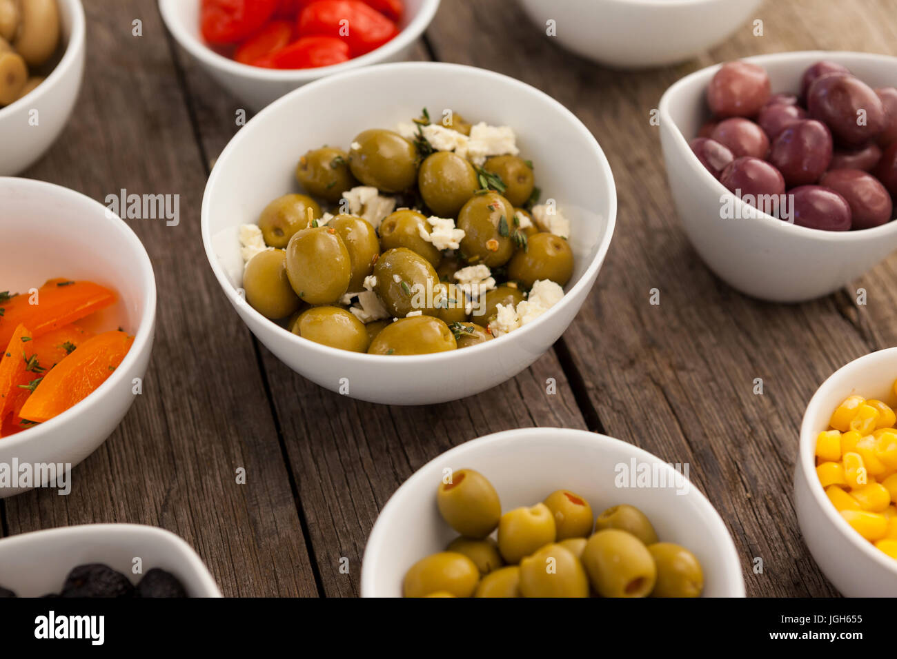 Various olives and ingredients in bowls on table Stock Photo