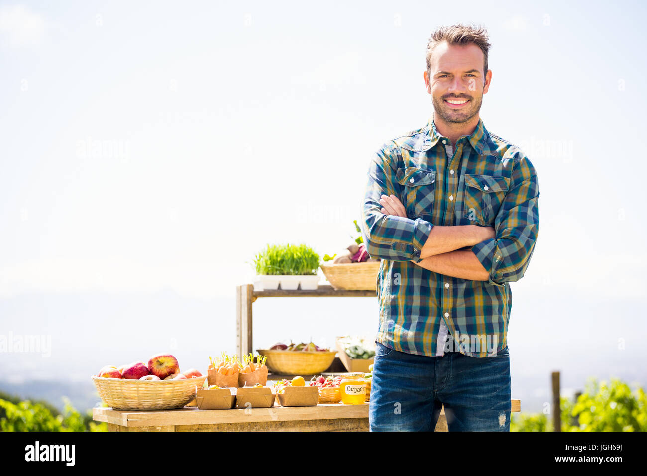 Portrait of smiling young man with arms crossed standing at farm Stock ...