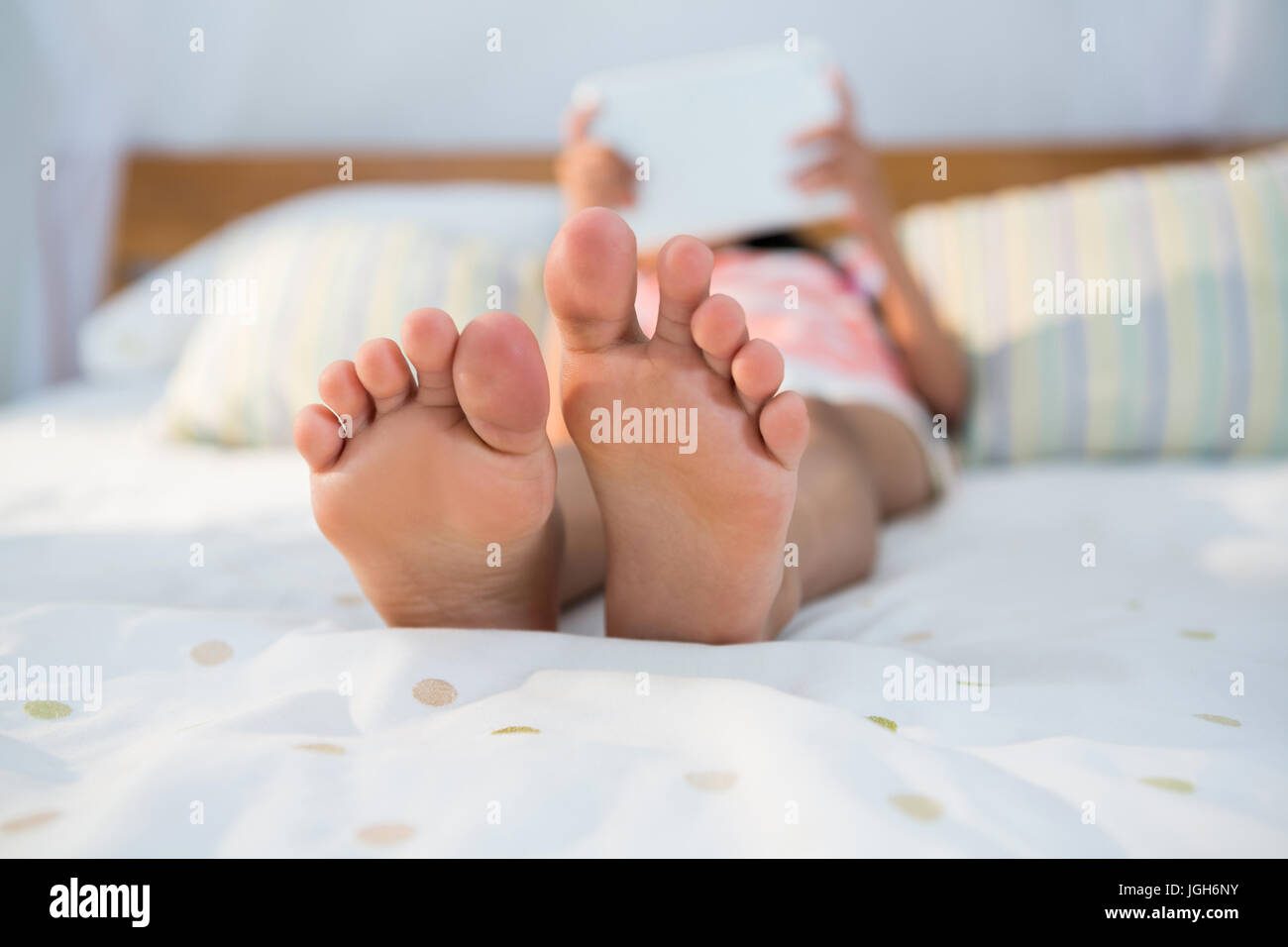 Girl lying on bed while using digital tablet at home Stock Photo - Alamy
