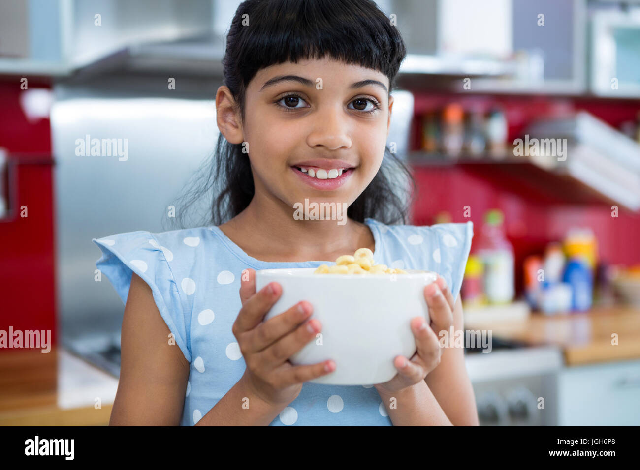 Close-up portrait of smiling girl with breakfast bowl in kitchen Stock Photo