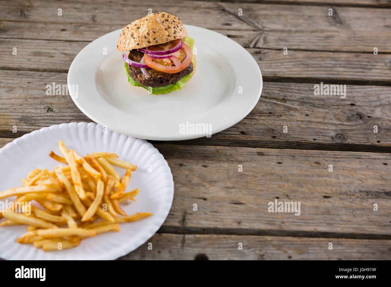 High angle view of french fries by hamburger served in plate on table ...