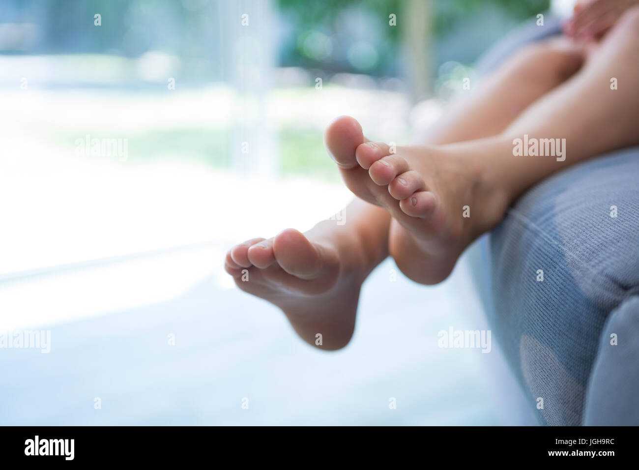 Girl sitting barefoot on sofa hi-res stock photography and images - Alamy
