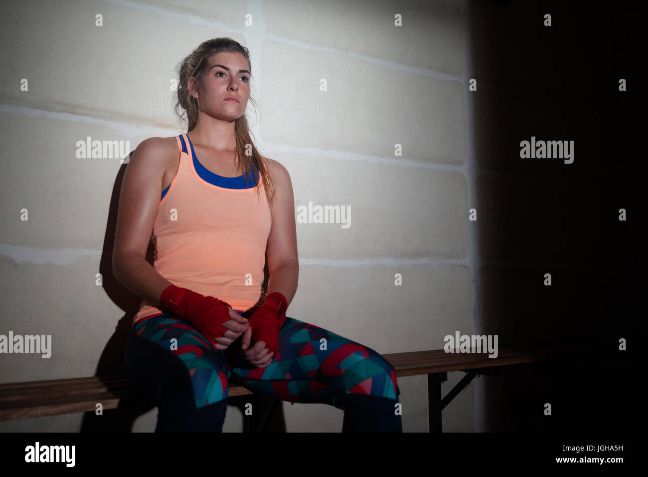 Thoughtful woman relaxing on bench in fitness studio Stock Photo - Alamy