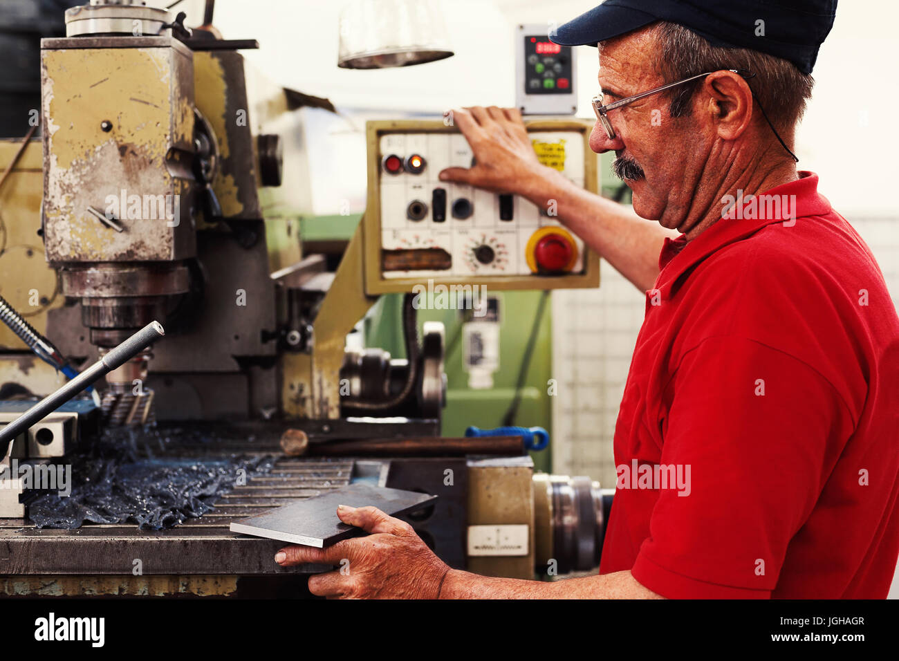 Worker in big industrial company, producing parts on his machine. Stock Photo