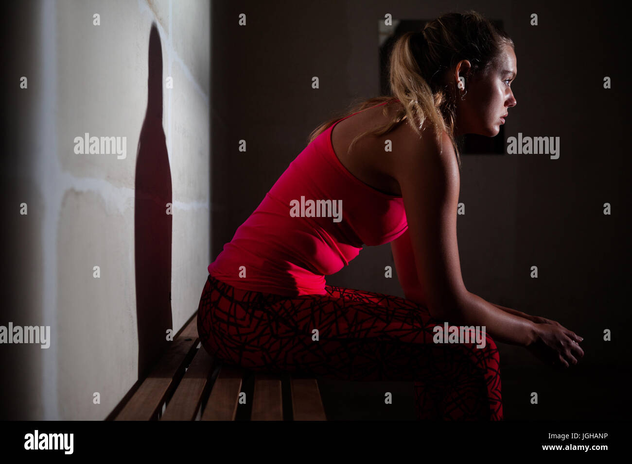 Thoughtful woman relaxing on bench in fitness studio Stock Photo - Alamy