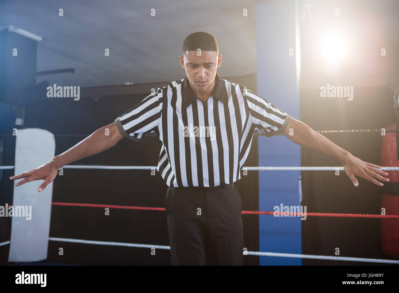 Male referee gesturing with arms outstretched in boxing ring Stock