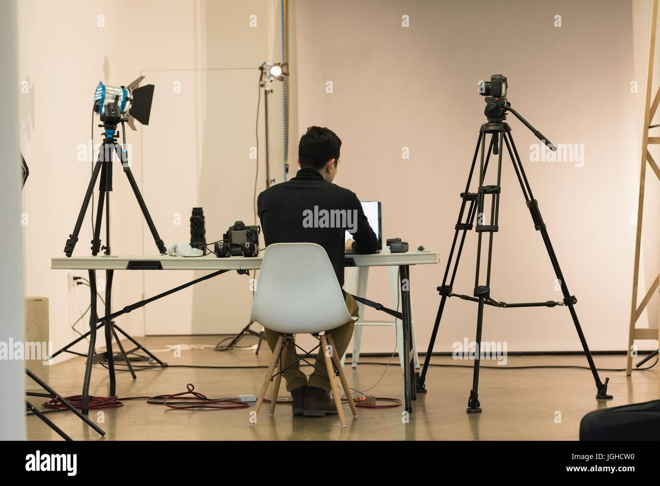 Rear view of photographer working while sitting on chair at studio Stock Photo