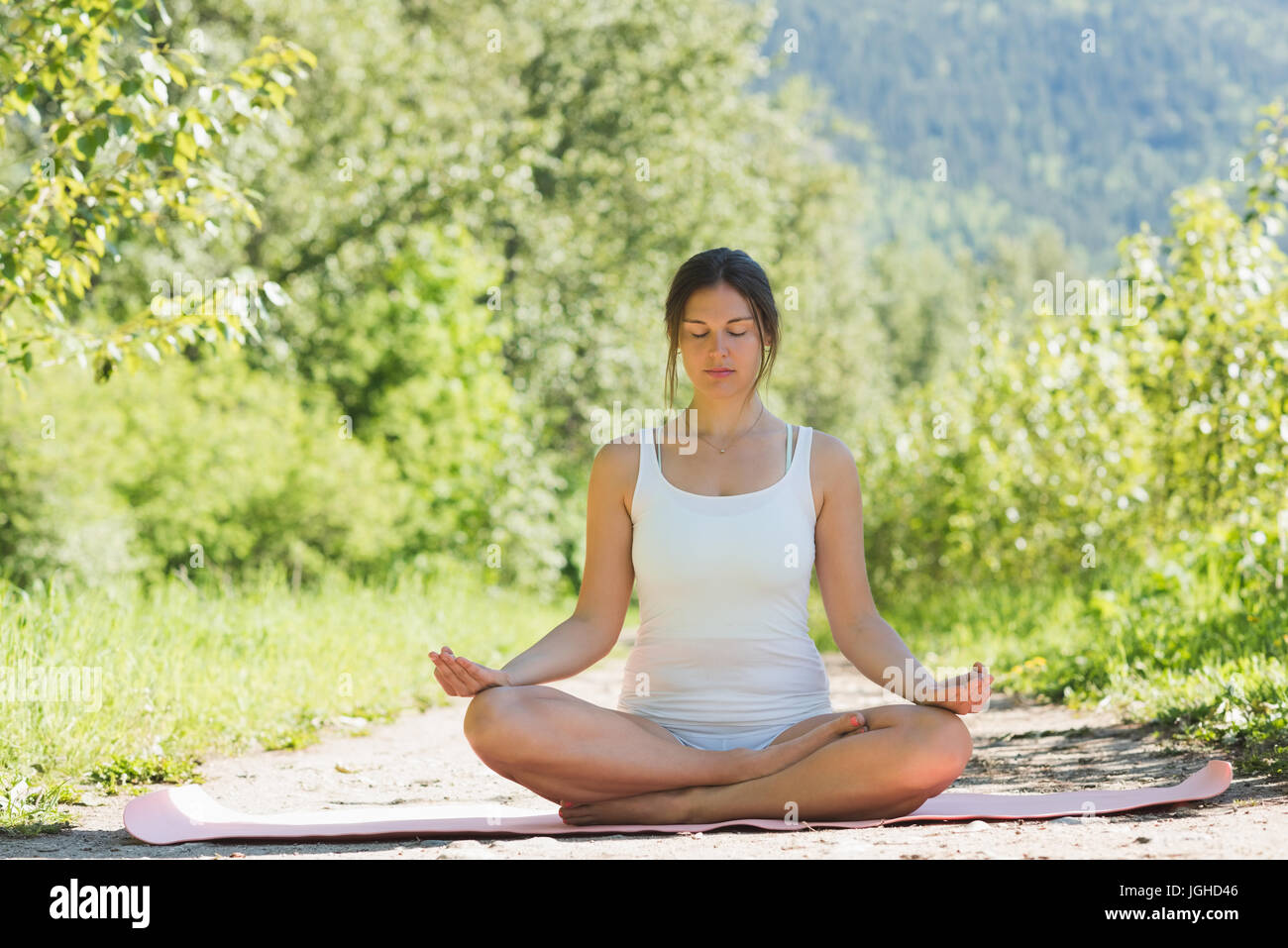 Woman doing meditation pose on yoga mat in forest Stock Photo - Alamy