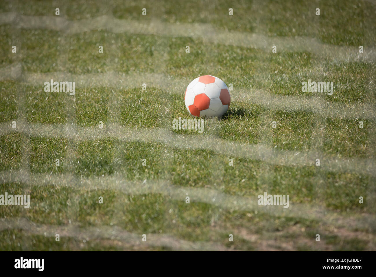 Soccer ball on playing field seen through net Stock Photo Alamy