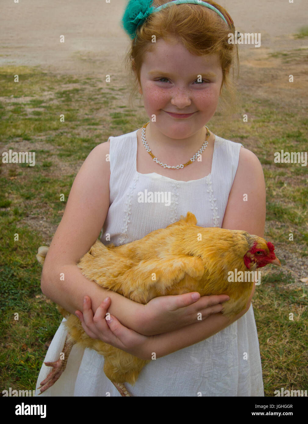 Red headed young girl holding hen on farm Stock Photo