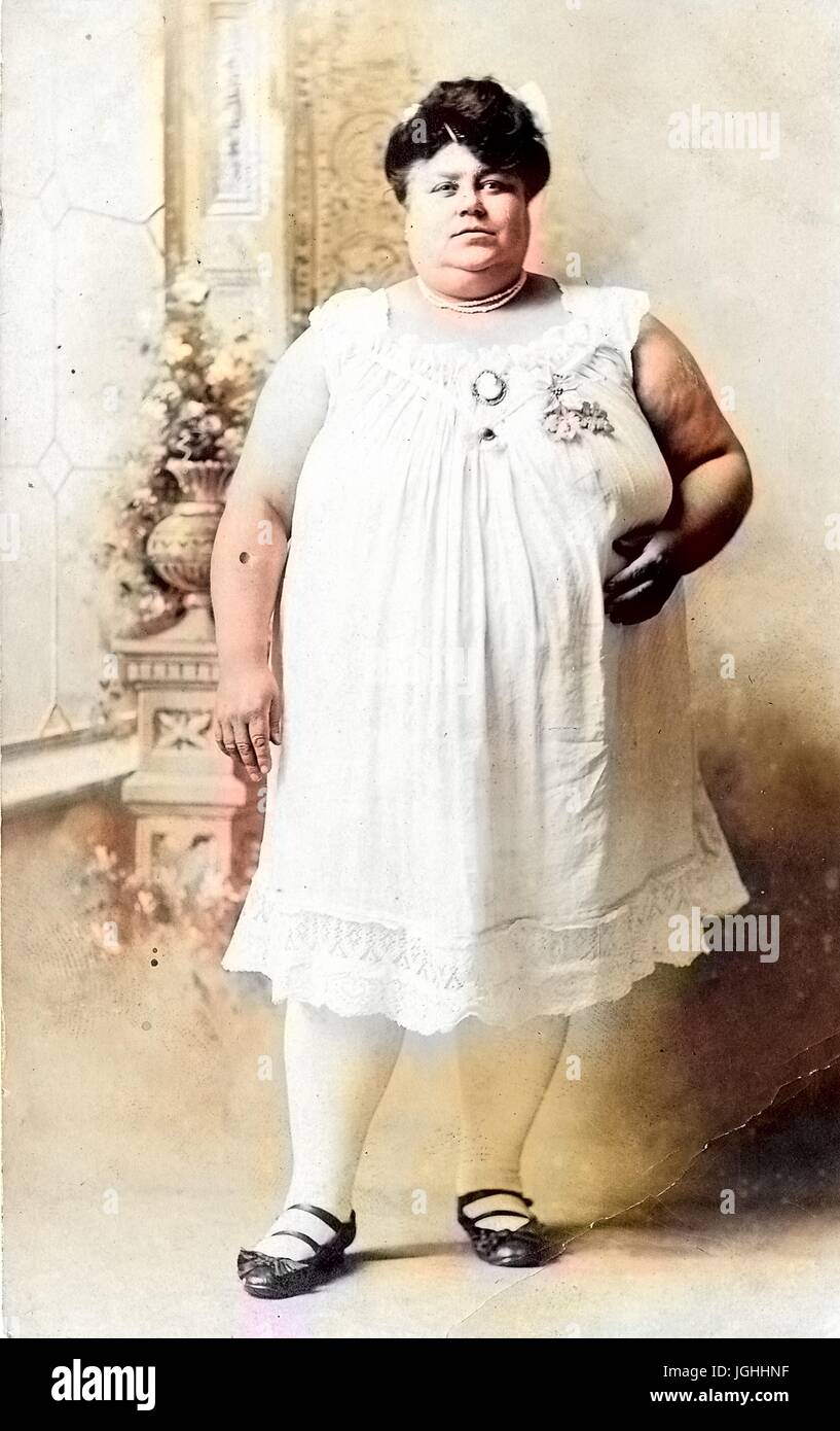 Portrait of an African American woman standing, named Miss Hazel Baldwin, wearing a white dress and black shoes at a carnival, August, 1914. Note: Image has been digitally colorized using a modern process. Colors may not be period-accurate. Stock Photo