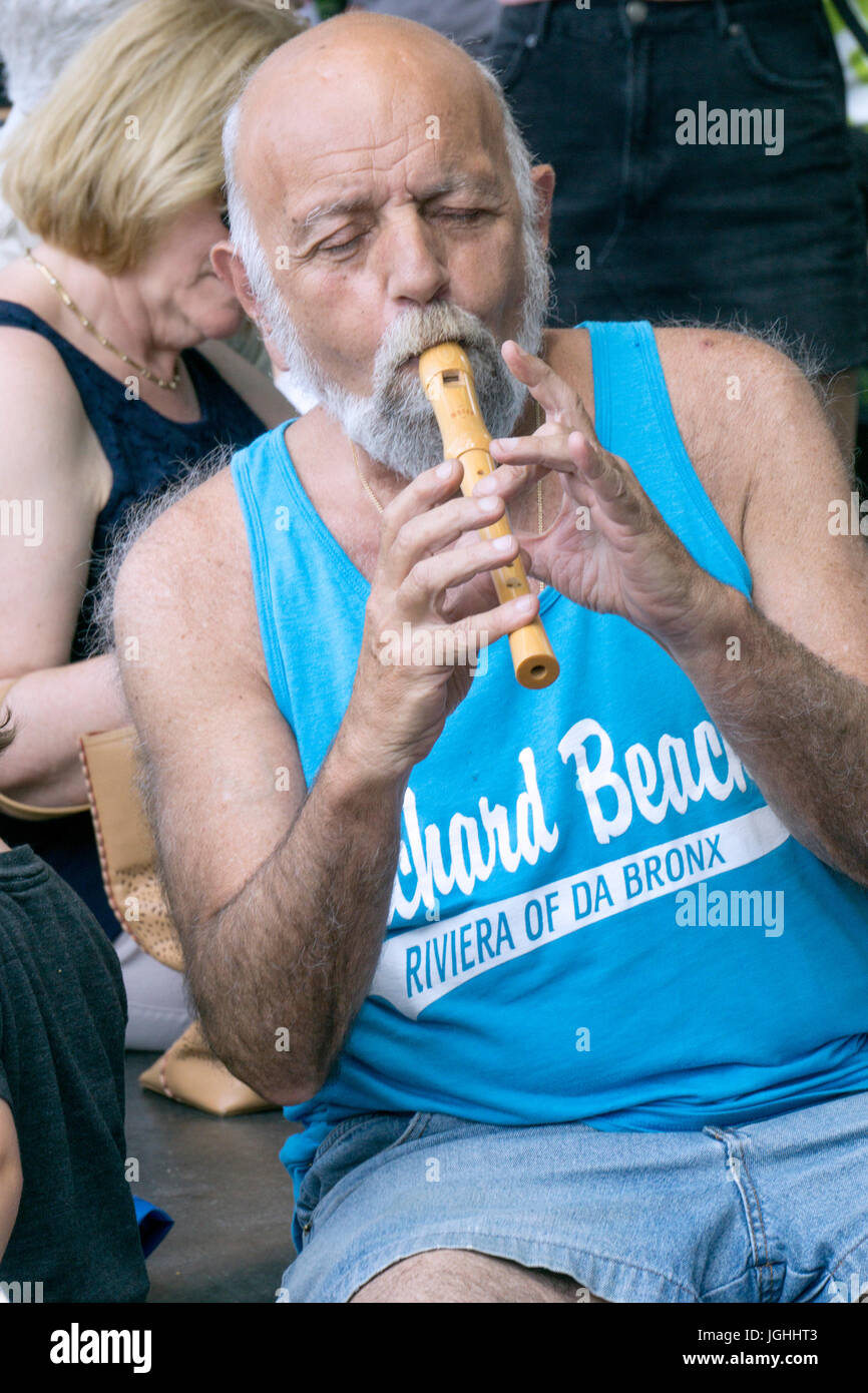 A middle age man performs with a group in Washington Square Park in Greenwich Village. The group has been performing there for several years. Stock Photo
