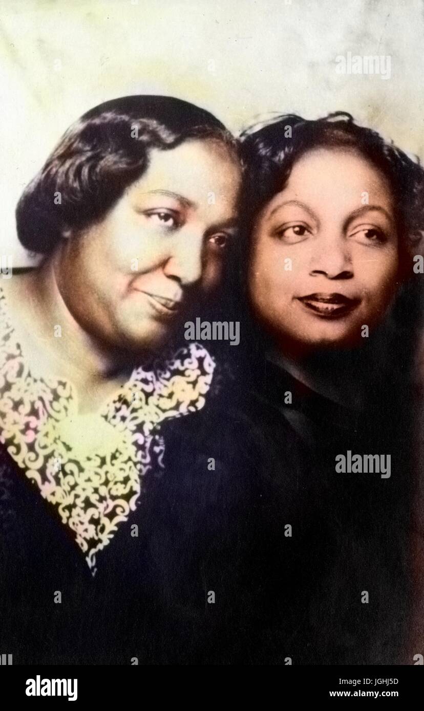Two African-American adult sisters, half length portrait, close up, the two sisters standing with their heads touching and looking off the frame, 1950. Note: Image has been digitally colorized using a modern process. Colors may not be period-accurate. Stock Photo