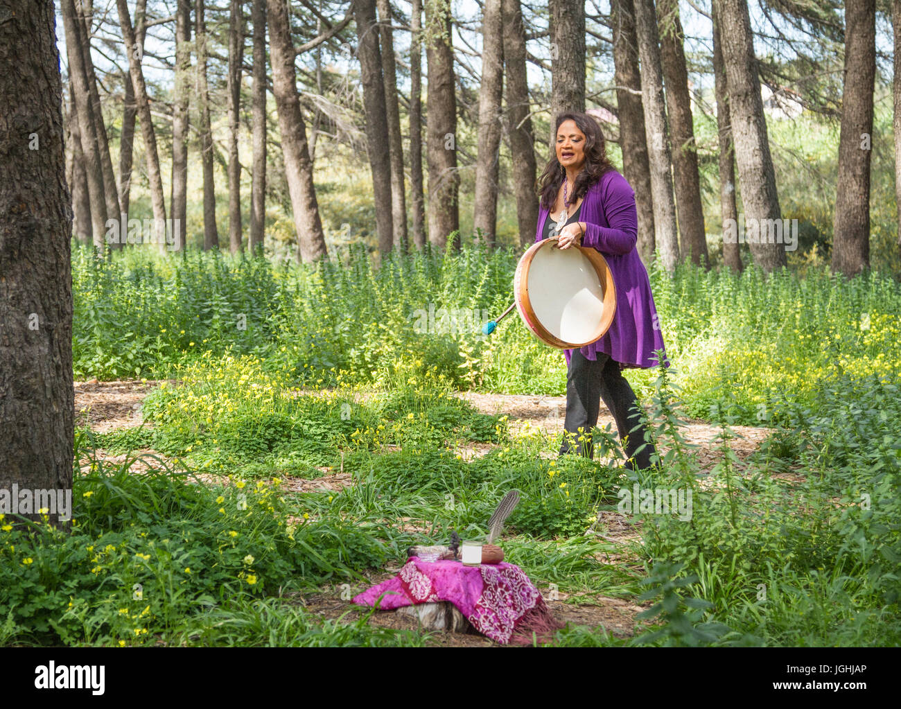 Female shaman drumming and chanting with altar Stock Photo