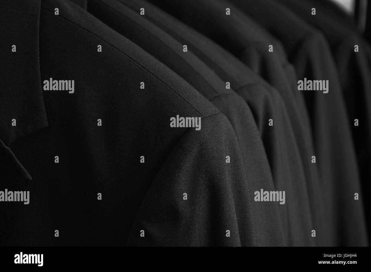 row of black tuxedo dinner jackets hanging in closet Stock Photo