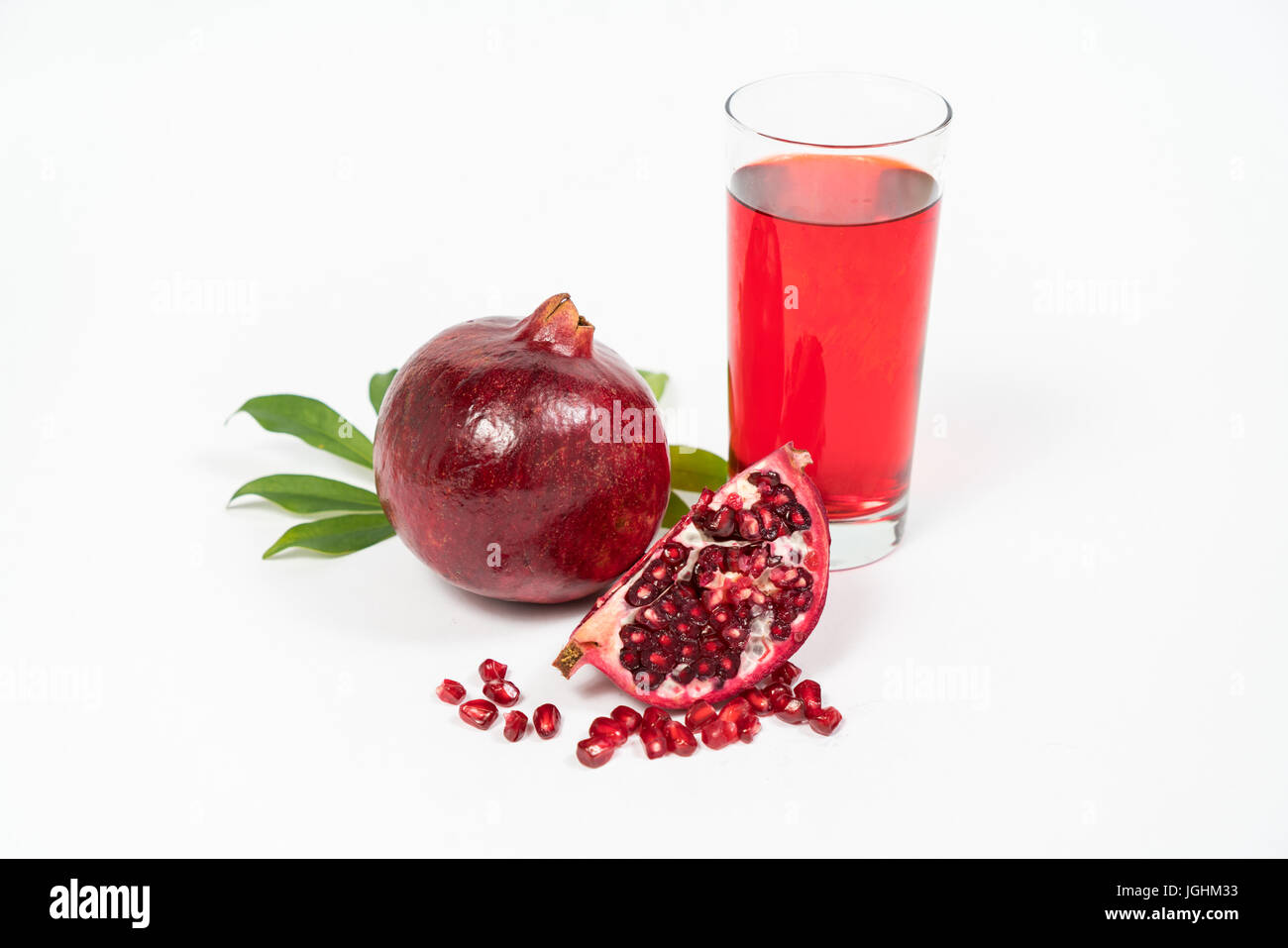 Fresh Pomegranate sliced with seeds and glass of juice on isolated white background Stock Photo