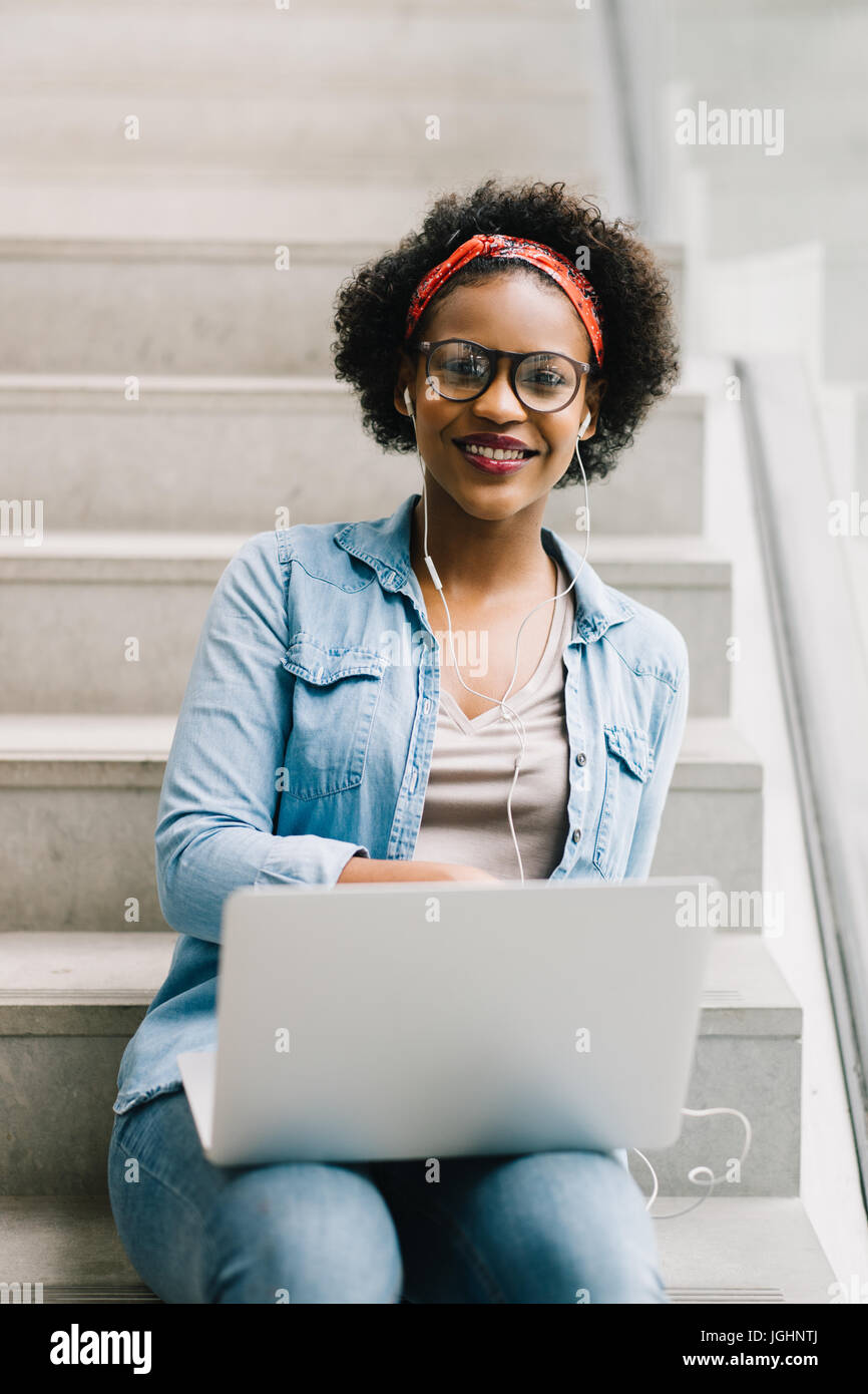 Smiling young African female entrepreneur smiling while sitting in a ...