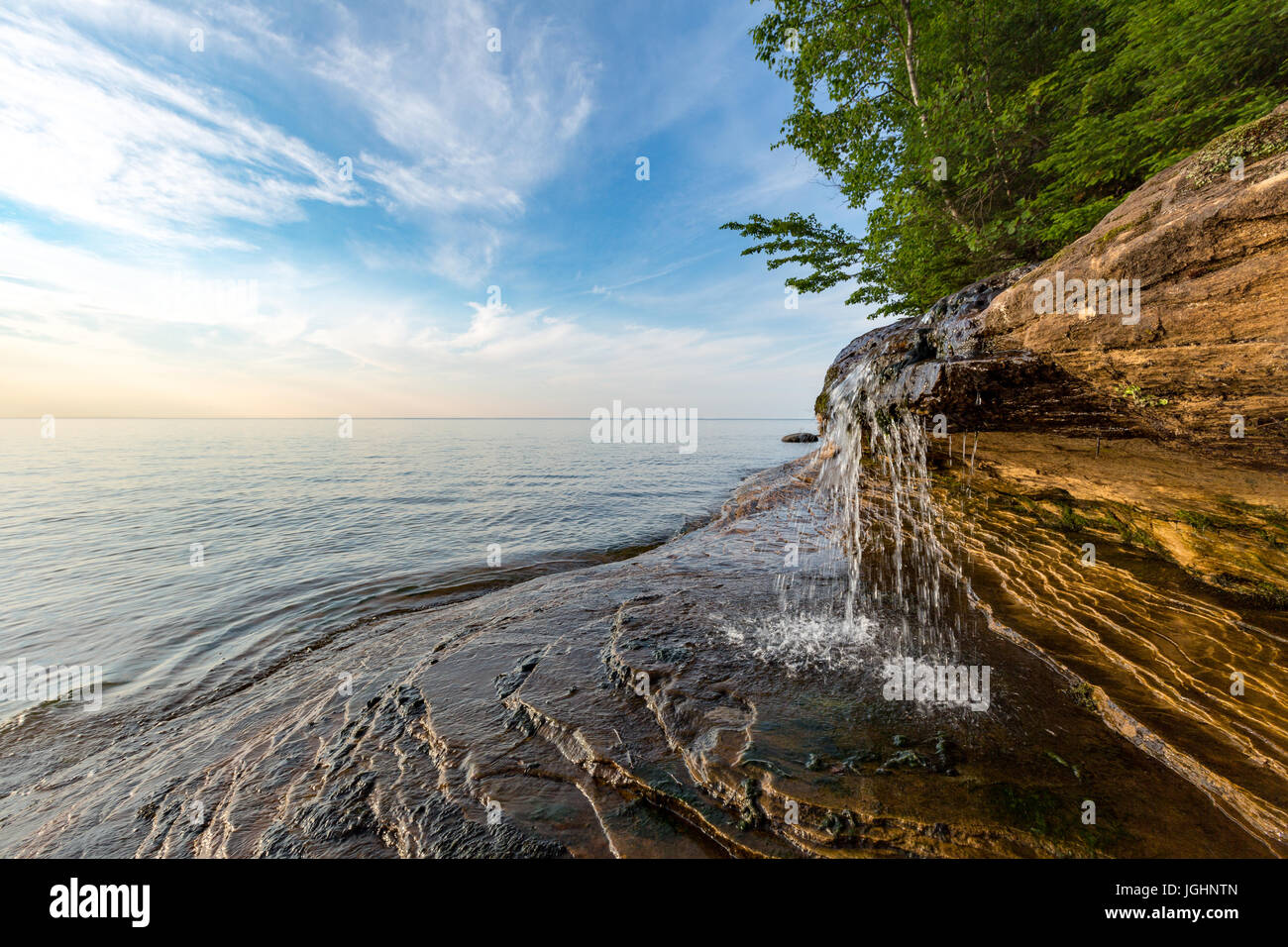Elliot Falls spills over sculpted rock at Pictured Rocks National Lakeshore in Munising Michigan. This little waterfall is on Miner's Beach. Stock Photo