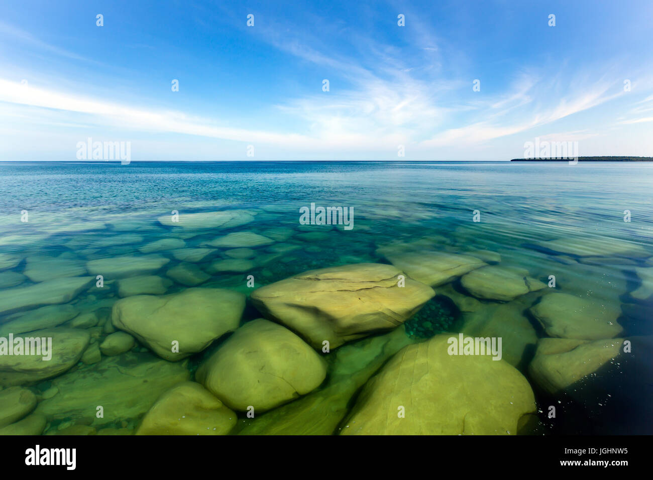 The clear waters of Lake Superior reveal large rocks and stones underwater. This cove, with pristine waters, is located near Au Train Michigan Stock Photo