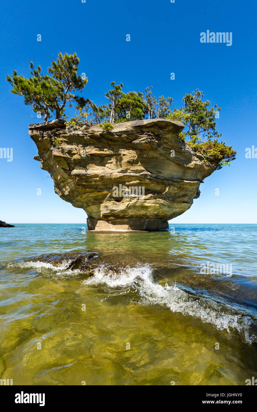 A Lake Huron wave splashes over a rock at Turnip Rock near Port Austin Michigan. Clear waters allow a view underwater Stock Photo