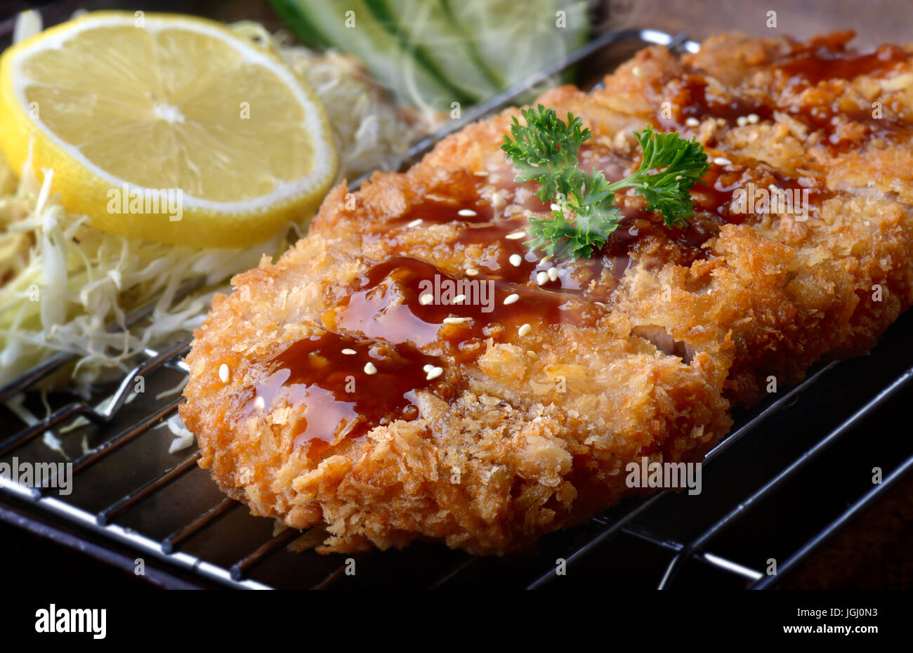 Japanese deep fried pork or tonkatsu with sauce fill on top in studio