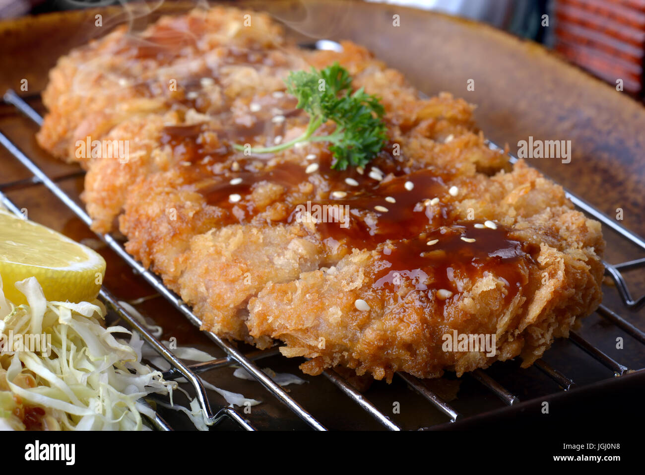 Japanese deep fried pork or tonkatsu with sauce fill on top in studio