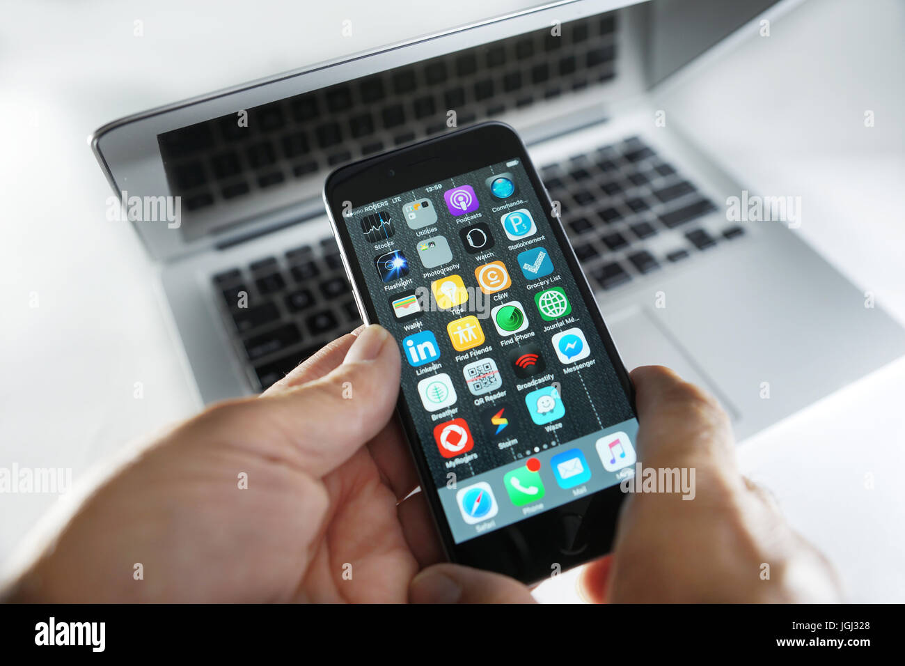 Montreal, Canada, 7 July, 2017. Hands holding an iphone 6 on top of a Macbook Air.Credit:Mario Beauregard/Alamy Live News Stock Photo