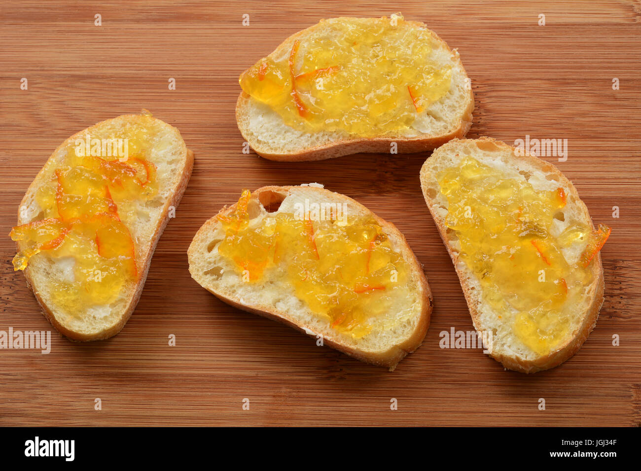 Small cibatta bread slices with seville orange marmalade on bamboo board in horizontal format Stock Photo
