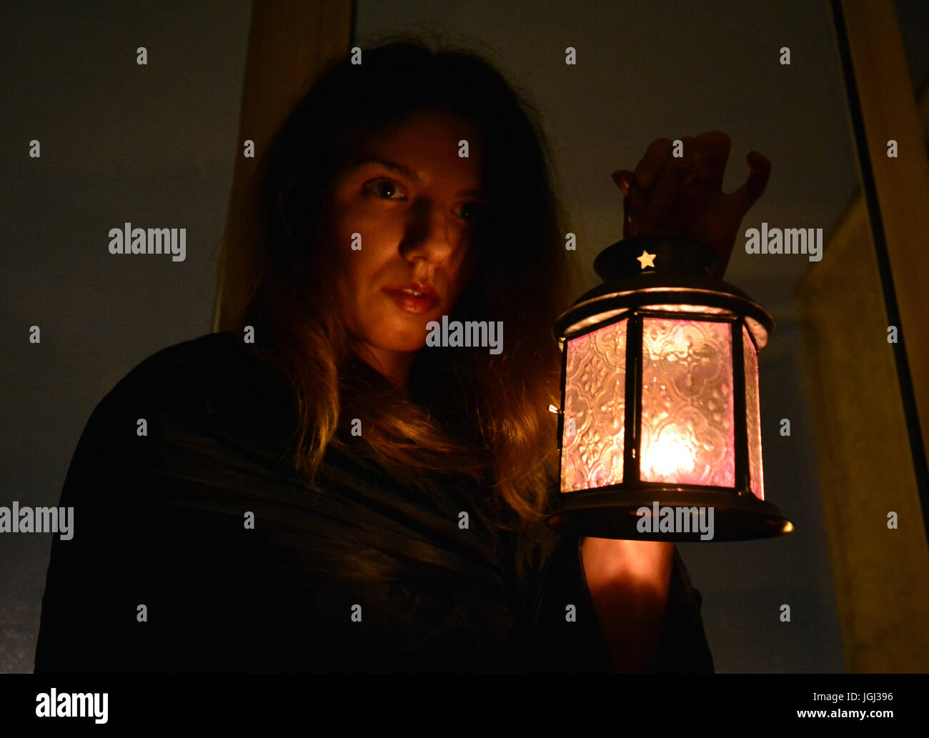 Woman holding a lamp to see through the dark Stock Photo - Alamy