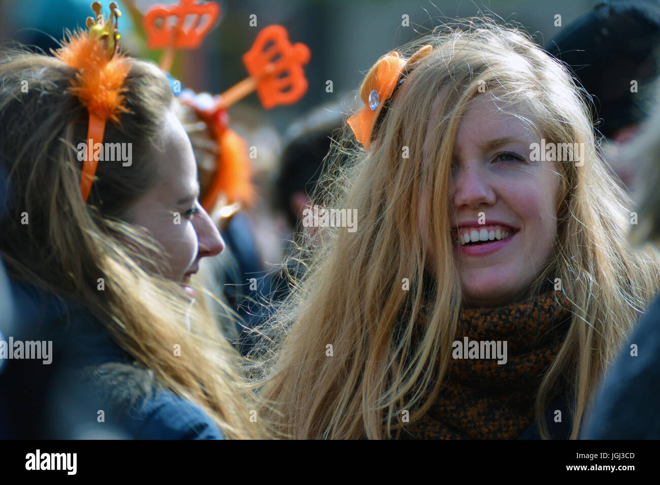A blonde girl having fun and drinking on Kingsdad or the King's Day in Groningen, Netherlands. Stock Photo