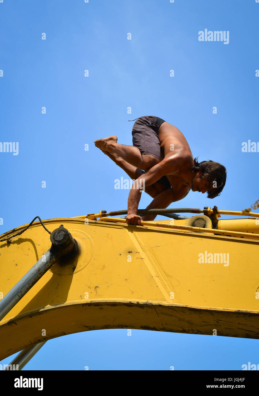 Indian worker doing yoga exercise on bulldozer at relaxing hour in the