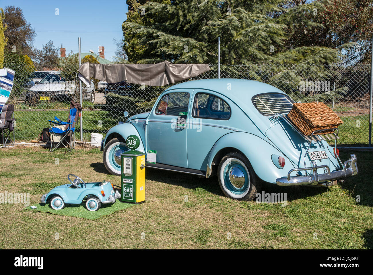 A Restored 1961 Volkswagen Beetle on display with a childs toy model VW and a small replica petrol bowser. Stock Photo