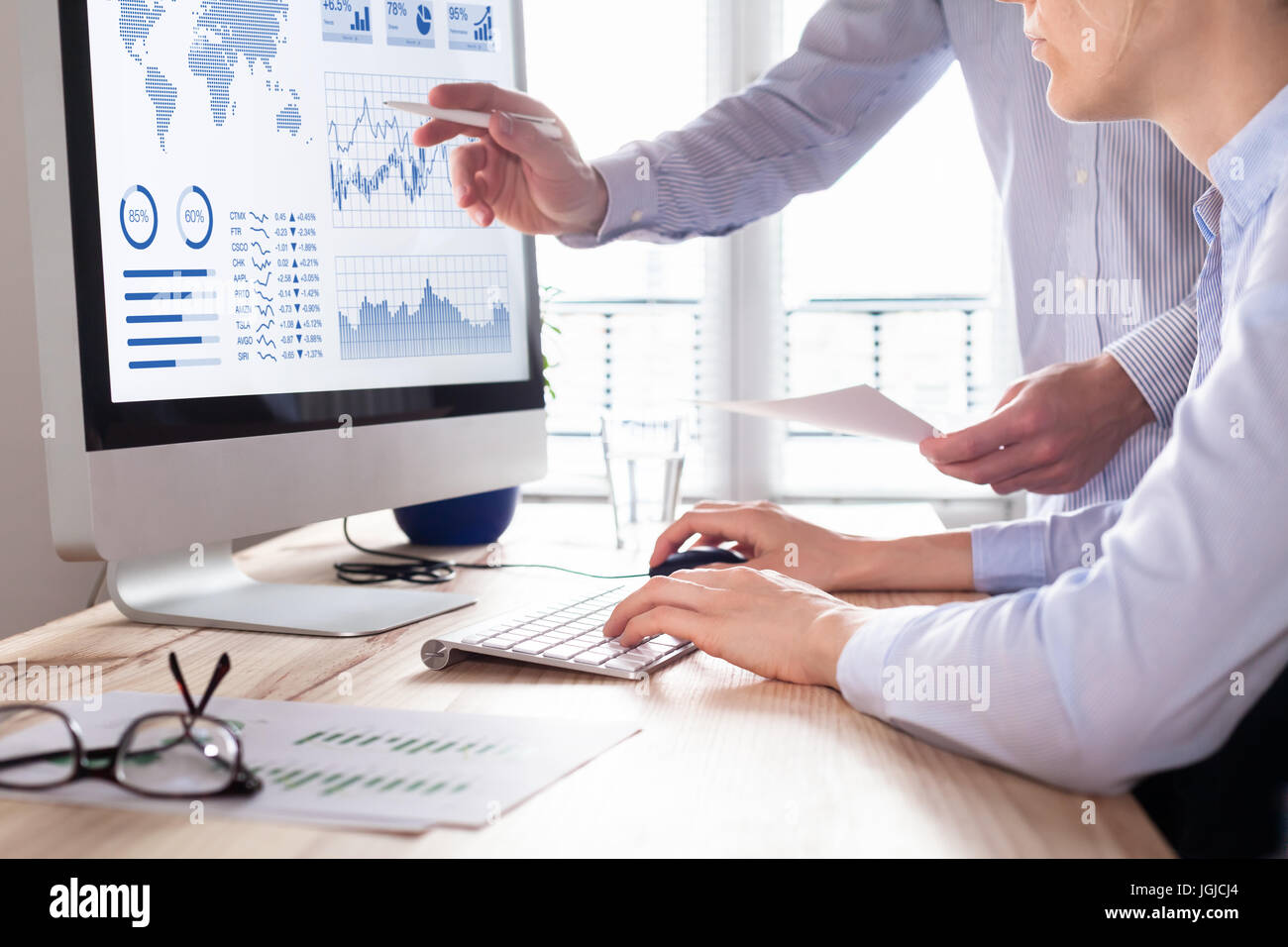Two people analyzing stock market investment strategy with key performance indicator on financial dashboard and business intelligence on computer Stock Photo