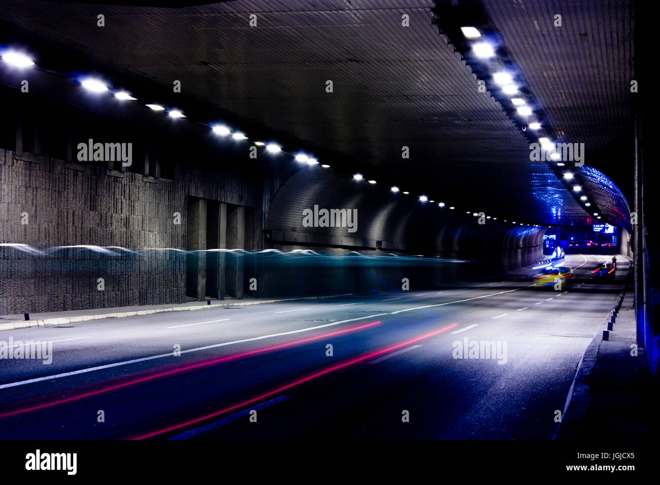 Night traffic on city streets. Vehicles getting in and out of the tunnel in motion blur Stock Photo