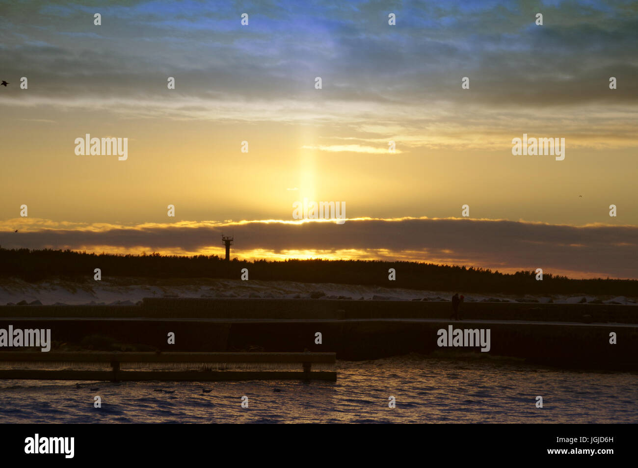 Light pillar atmospheric optical phenomenon on sunset by the sea in winter Stock Photo