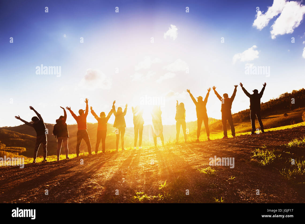 Big group of friends raising arms on sunset together Stock Photo