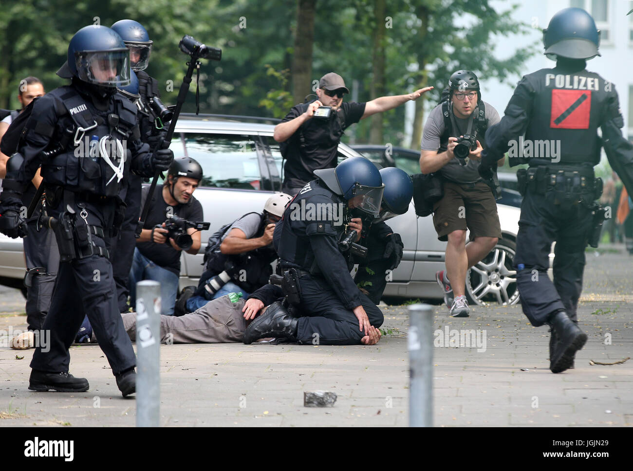 Hamburg, Germany. 7th July, 2017. Policemen arrest an activist while journalists watch near Landungsbruecken station in Hamburg, Germany, 7 July 2017. The heads of the governments of the G20 group of countries are meeting in Hamburg on the 7-8 July 2017. Photo: Sebastian Willnow/dpa/Alamy Live News Stock Photo