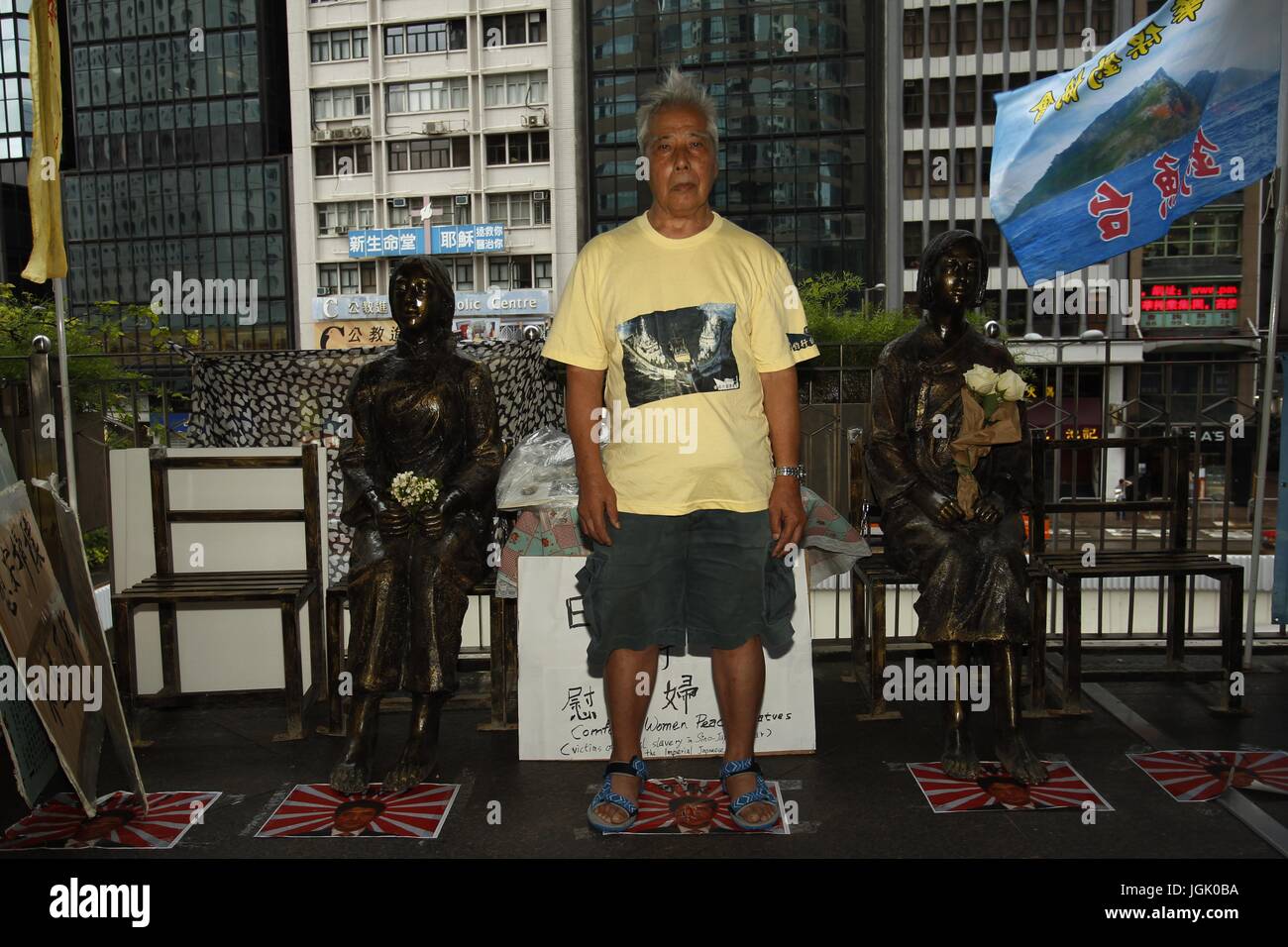 July 8, 2017 - Hong Kong, CHINA - Member of the Patriotic Organization steps on the printed image of present Japanese Prime Minister Shinzo Abe with pair of bronze statue of [Comfort Women] on left ( Chinese woman ) and right ( Korean woman ). To commemorate 80th anniversary of 7-7, 1937 breaking out of 8 years War against Japan, a local Patriotic Organization have set up pair of bronze statue of Chinese & Korean [Comfort Women] on the flyover adjacent to Consulate General of Japan in Hong Kong. Consulate General is requesting bronze statues to be removed but no actions have been taken so far. Stock Photo