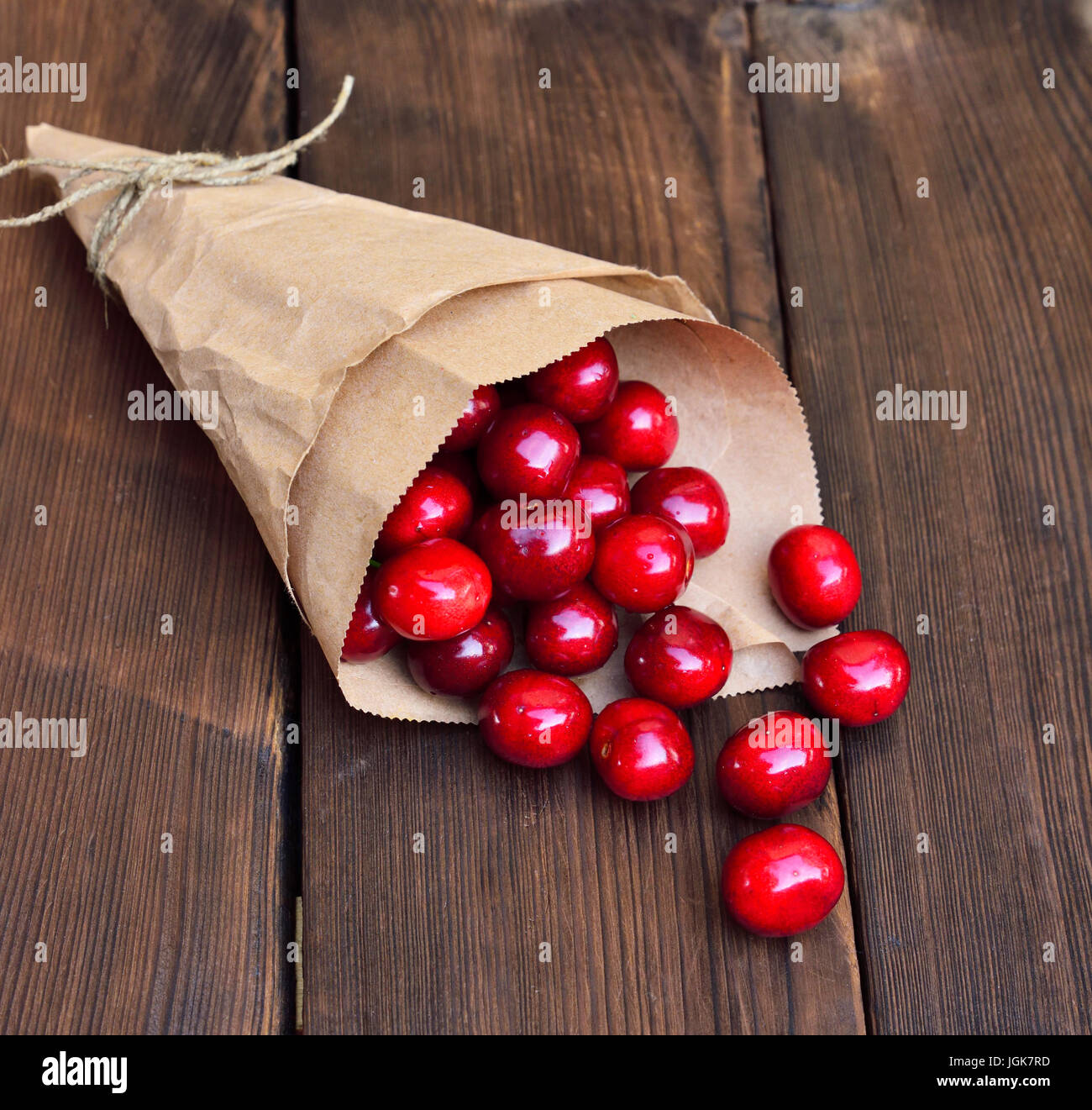 Ripe red cherry in a paper bag on a brown wooden background Stock Photo ...
