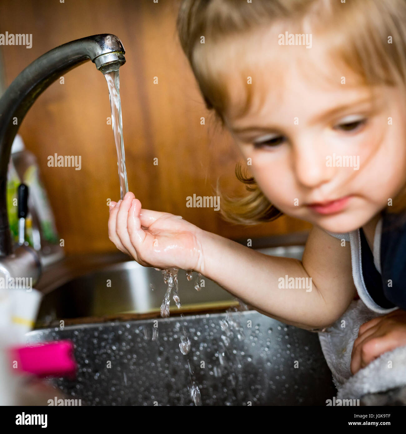 hand of a baby under the water streaming out of a faucet as the face of the  little girl is out of focus - water dripping concept Stock Photo - Alamy