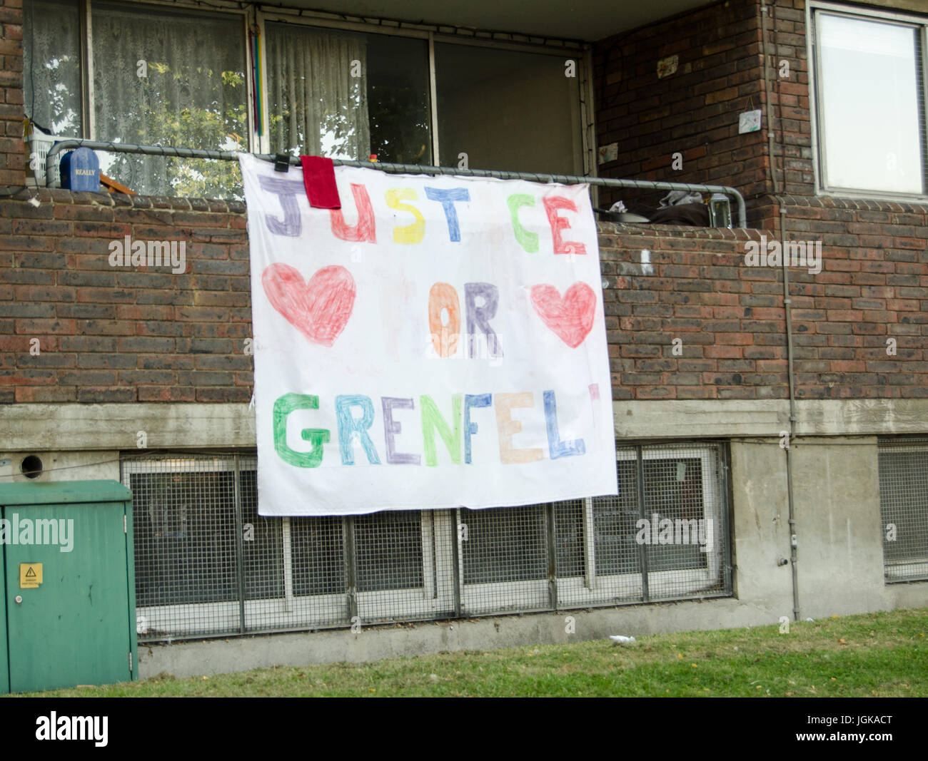 Hand drawn banner calling for Justice for Grenfell displayed on the balcony of a flat next to the Grenfell Tower block in which at least 80 people wer Stock Photo