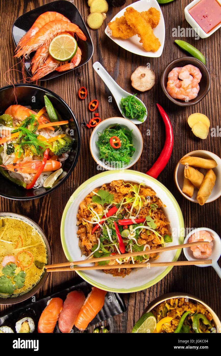 Asian food table with various kind of chinese food, noodles, chicken, pork,  beef, rice, spring rolls, sushi, prawns and many others. Served on old woo  Stock Photo - Alamy