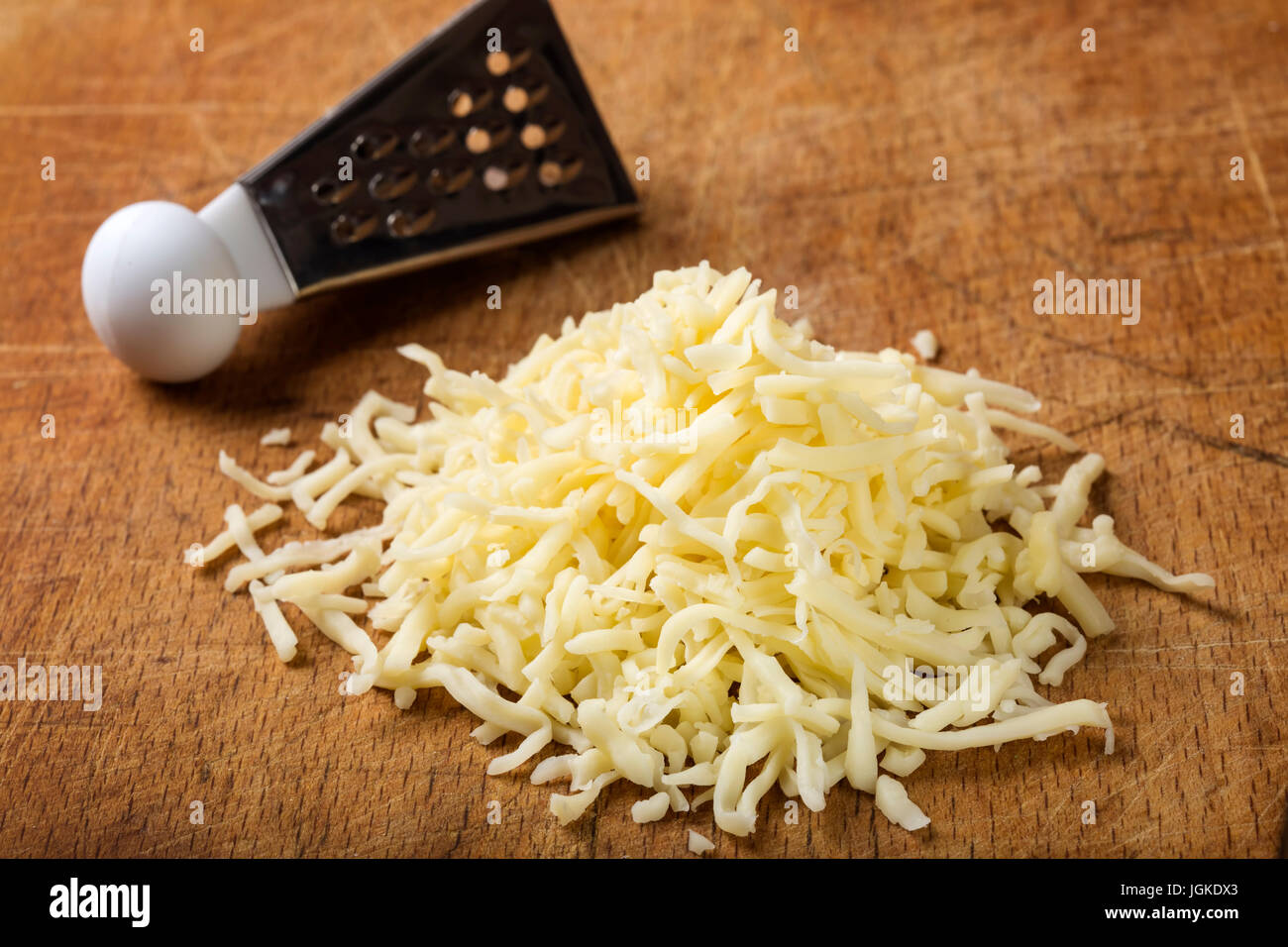 Close up of freshly grated parmesan cheese on wooden table Stock Photo