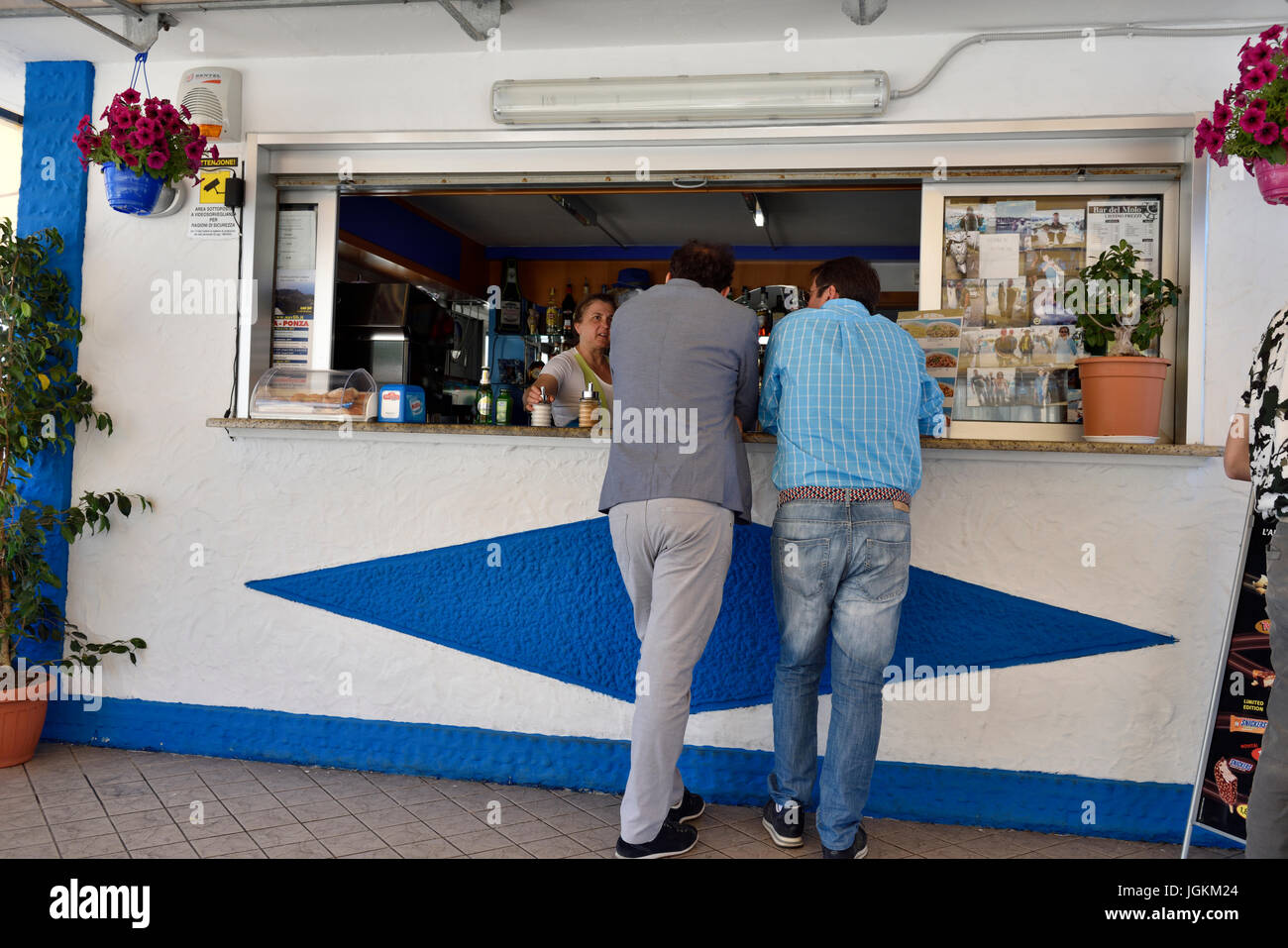 The backs of two men looking in the serving window of dinner Stock Photo