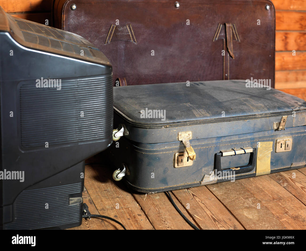 Abandoned old suitcases and TV set on the wooden floor, indoor cropped image Stock Photo