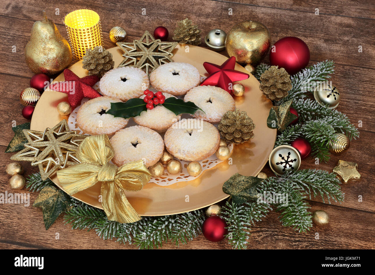 Christmas mince pies on a gold plate, bauble decorations, holly, fir ...