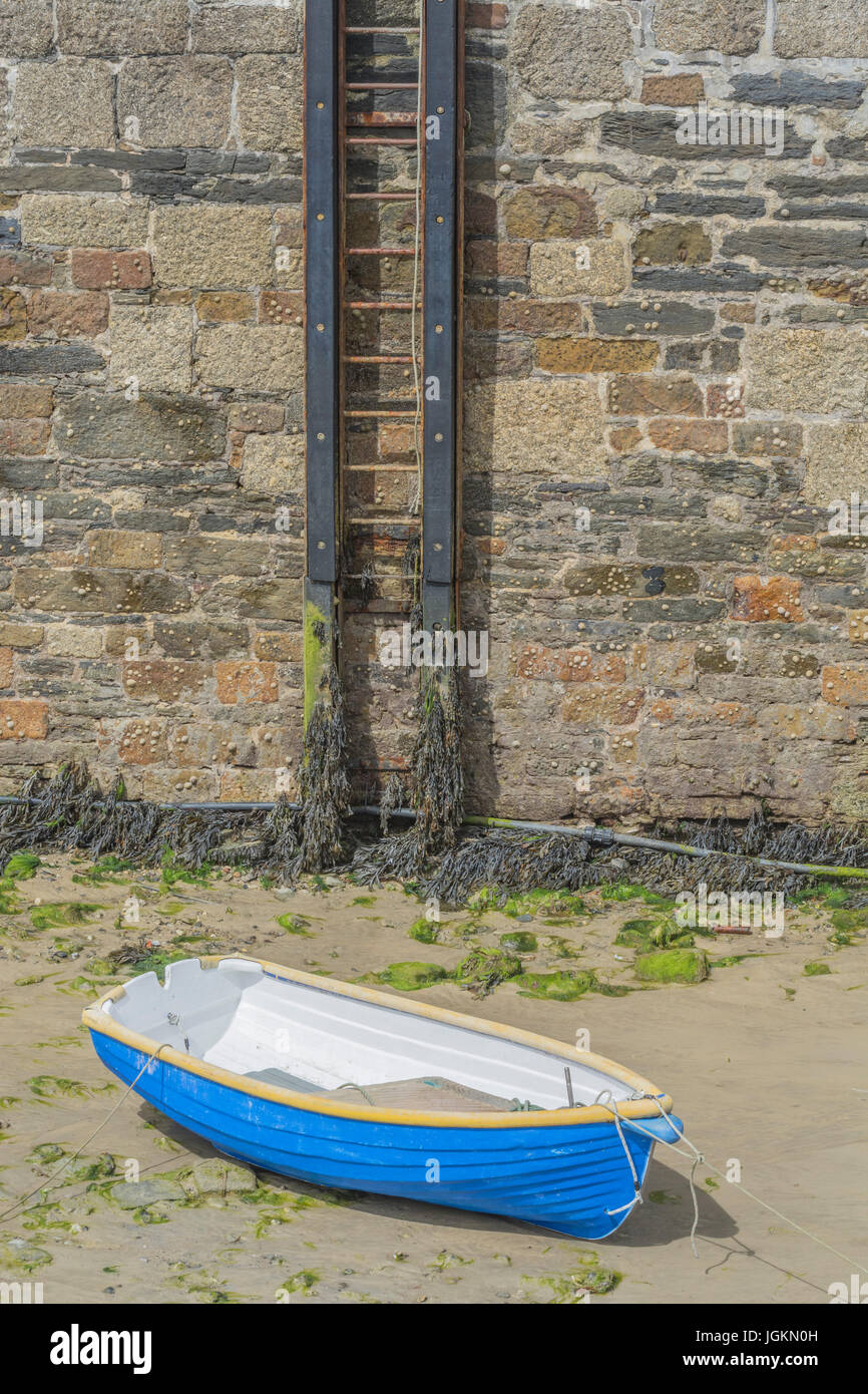 Quayside ladder and small sculling boat at Newquay harbour, Cornwall. Metaphor for career ladder, or getting on the property ladder. Stock Photo