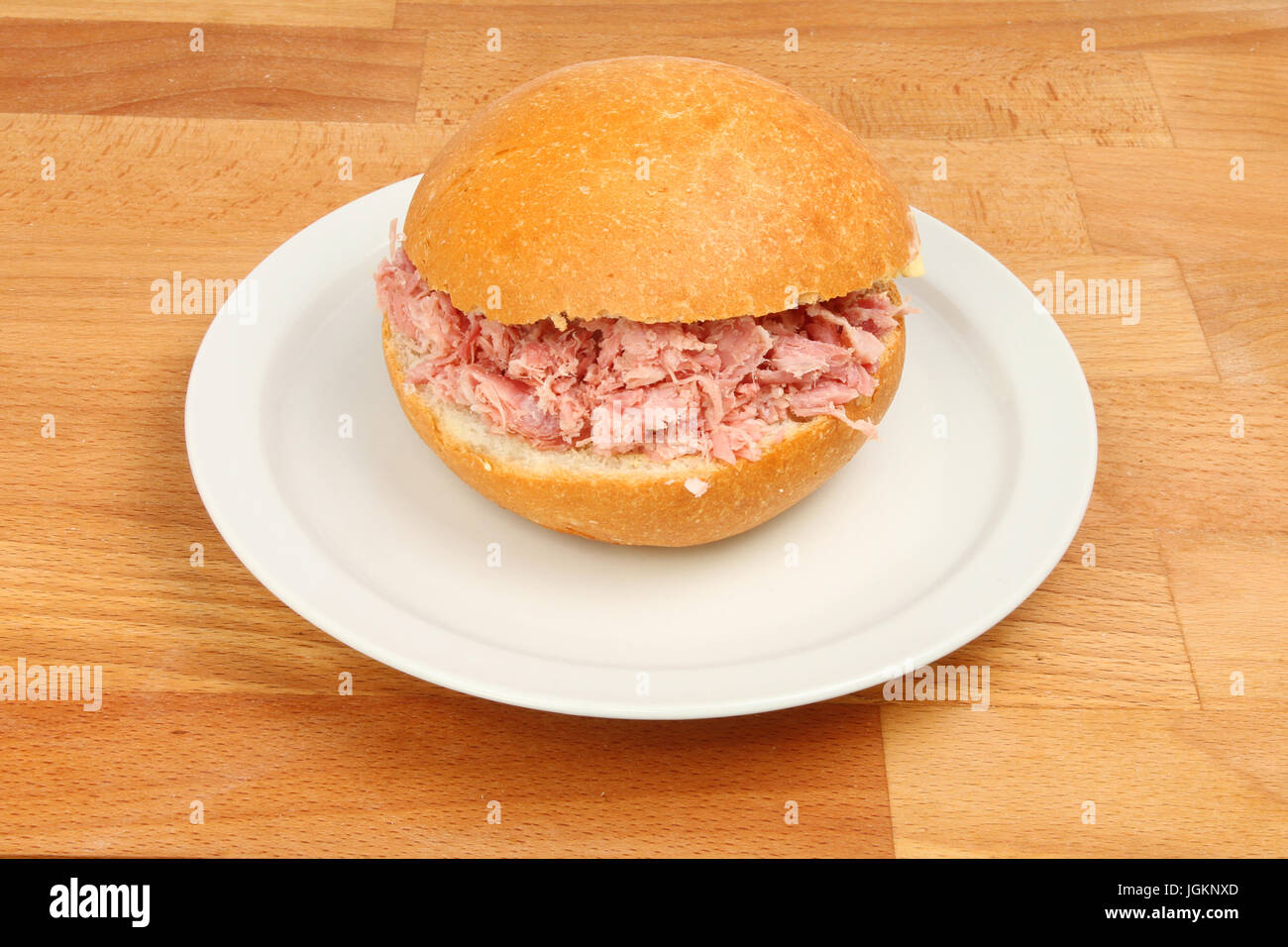 Pulled pork in a crusty roll on a plate on a wooden tabletop Stock Photo
